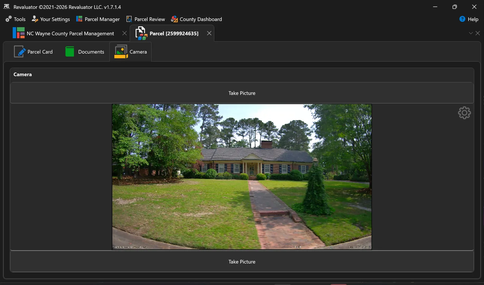 Camera panel inside Revaluator showing a captured photograph of a single-storey brick house, ready to attach to the parcel record.